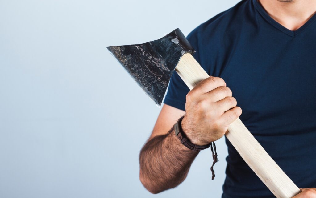 Man facing the camera holding an axe.