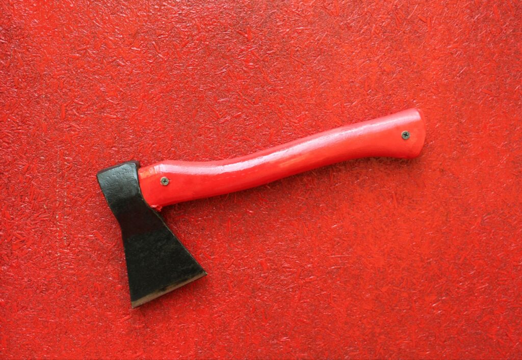A simple red-handled axe rests on a red background.