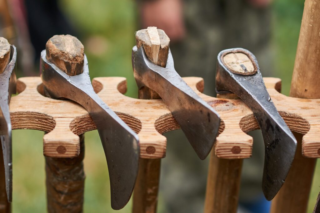 A series of axes in a wooden rack.