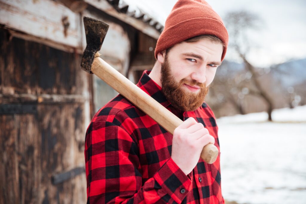 Smiling bearded man holding an axe over his shoulder.