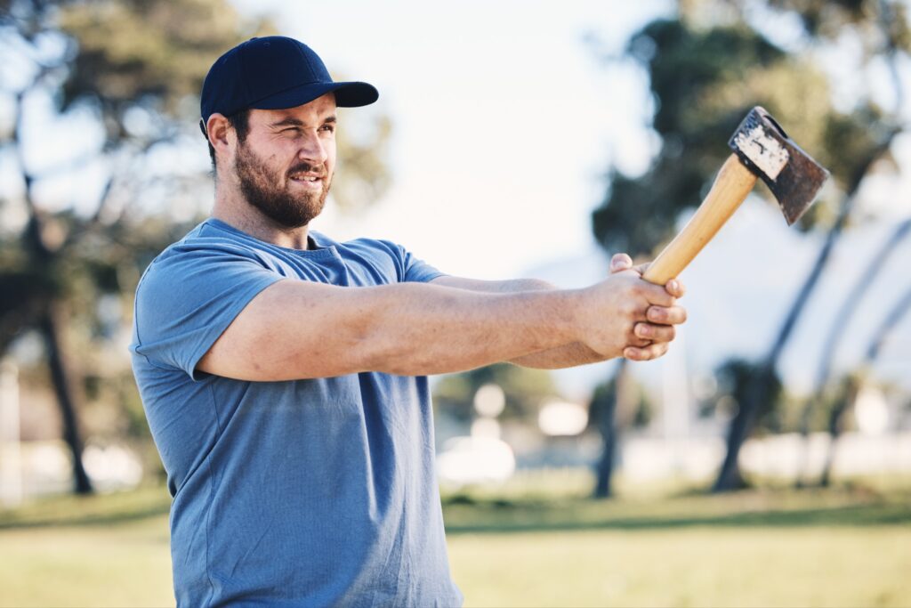 A man in a blue shirt holds an axe, preparing to throw it.