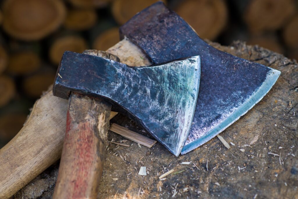 Two rustic axes lying on top of a wooden stump.