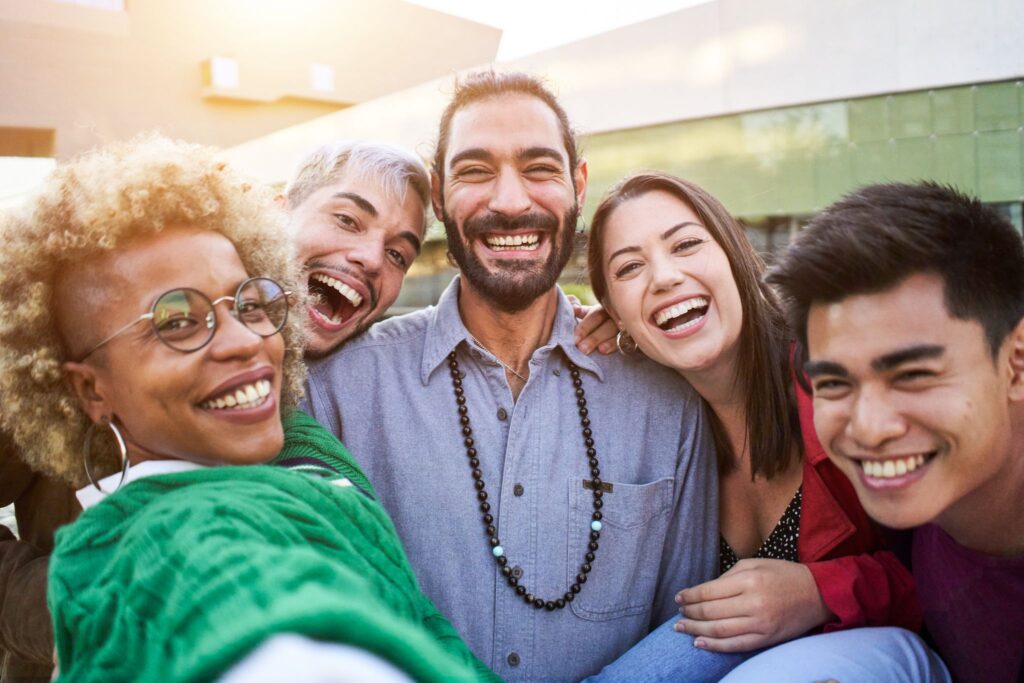 A group of friends smiling and laughing as they take a selfie.