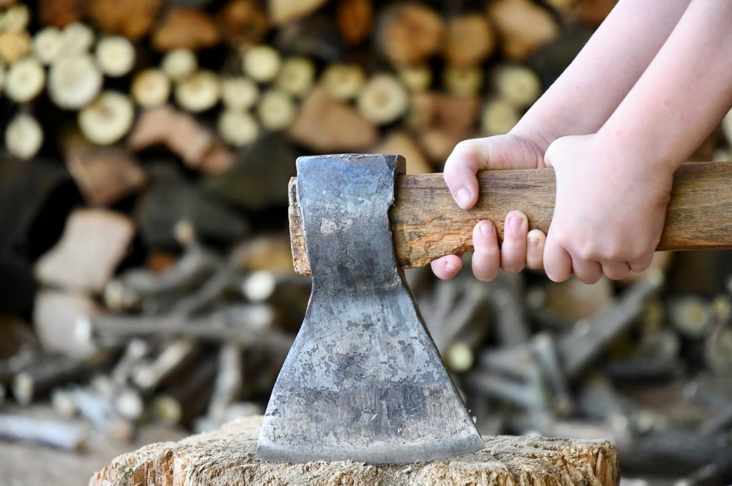 Two hands holding an axe above a wood stump.