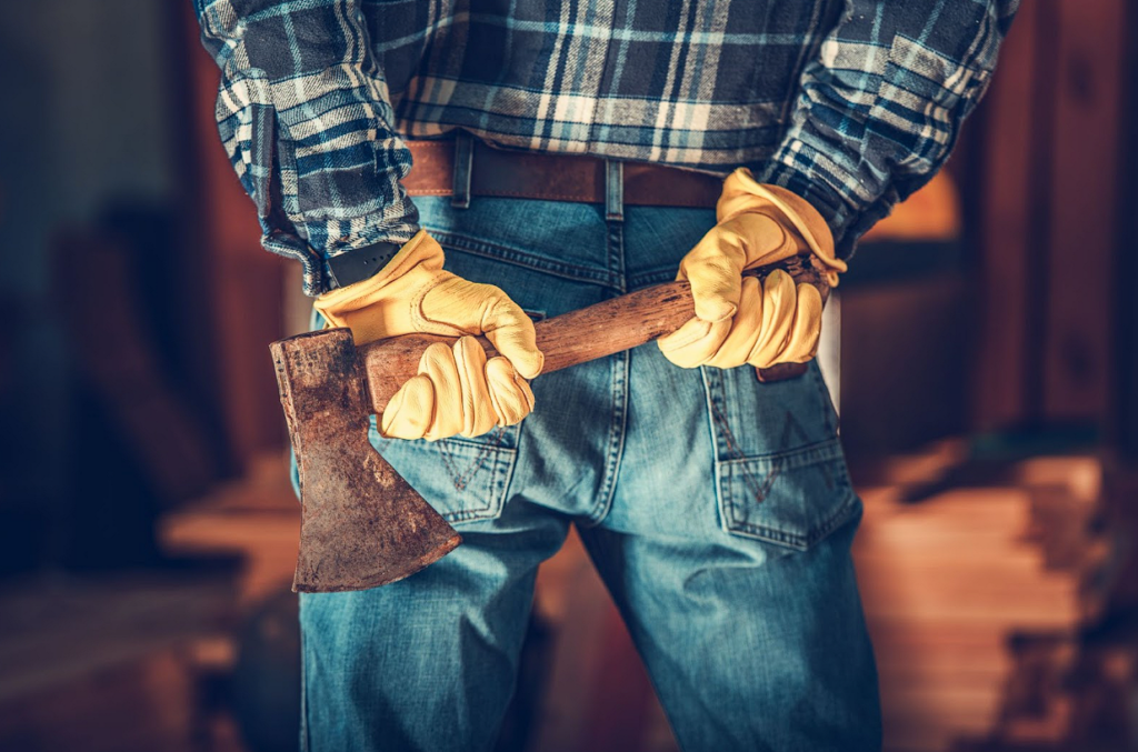A lumberjack with an axe behind his back. He is wearing yellow work gloves.