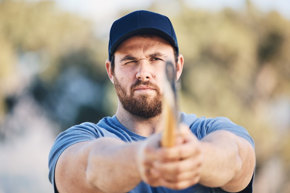 Man with an axe with his eye closed as he aims at a target.