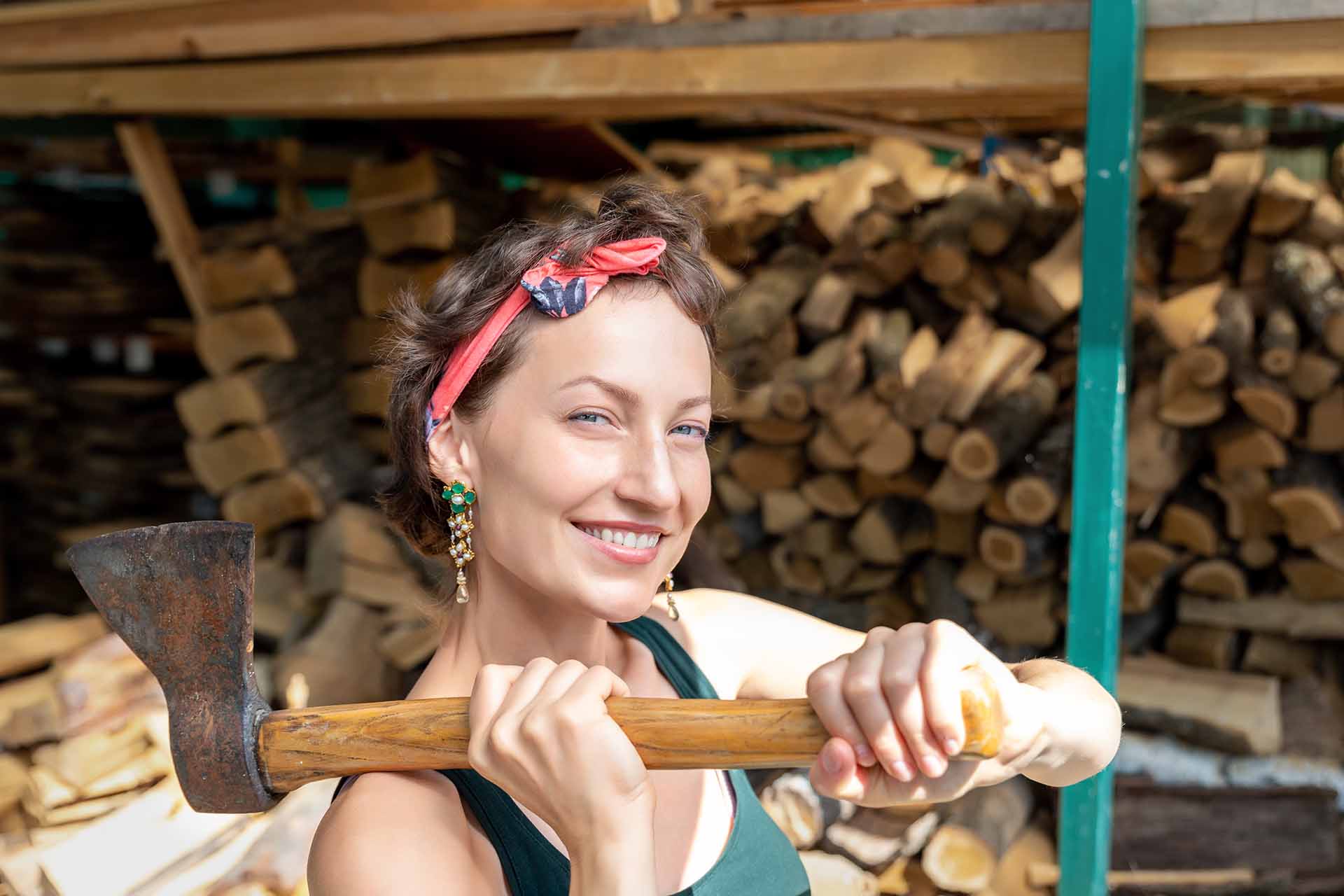 A woman wearing a green sleeveless is holding an axe.